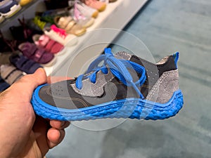 POV male hand holding shopping blue children shoe