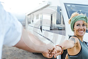 Pov of man holding woman hands and modern camper van motorhome in background. Happy couple enjoy alternative vanlife life and