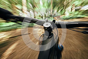 POV, mountain bike and person cycling in nature, park and forest for adventure, speed and motion blur. Closeup