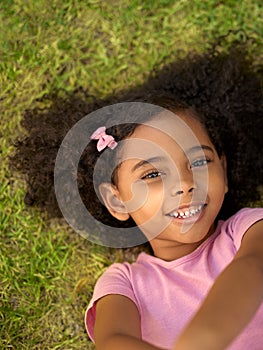 POV Overhead Shot Of Smiling Girl Lying On Grass Taking Selfie On Mobile Phone