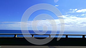 POV-Passenger side window driving scene. blue ocean against  blue sky