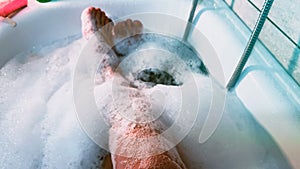 POV person lying in a bath tub filled with water and soap bubble foam. Take bubble bath for relaxation. Lying in bath