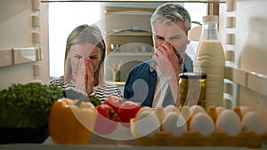 POV Point of view from inside fridge adult couple feeling bad disgusting unpleasant smell from broken refrigerator