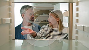 POV point of view from inside refrigerator adults middle-aged Caucasian couple family look at empty fridge nothing to