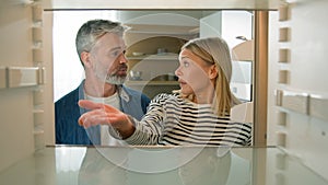 POV point of view from inside refrigerator adults middle-aged Caucasian couple family look at empty fridge nothing to