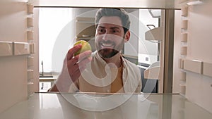 POV point of view from inside refrigerator Caucasian adult happy man at kitchen open empty fridge take last green apple