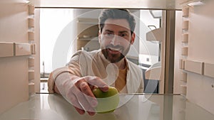 POV point of view from inside refrigerator Caucasian adult happy man at kitchen open empty fridge take last green apple