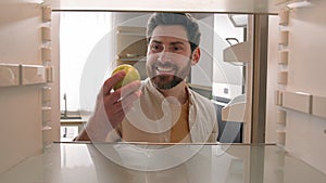 POV point of view from inside refrigerator Caucasian adult happy man at kitchen open empty fridge take last green apple