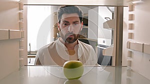POV point of view from inside refrigerator Caucasian adult man at kitchen open empty fridge with one green apple fruit