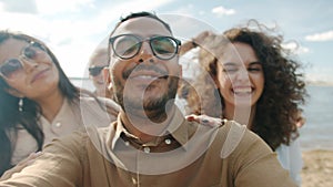 POV portrait of cheerful Arab man dancing outdoors with group of friends laughing enjoying beach party