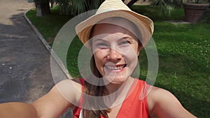 POV portrait of woman in green park. Female traveler smiling and making selfie in slow motion