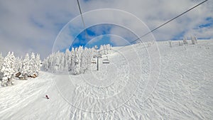 POV: Riding the ski lift over the tracked slopes of a ski resort in Slovenia.