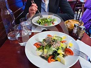 POV of Salad NiÃÂ§oise and Woman Eating in French Restaurant photo