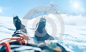 POV shoot of a high altitude mountain climber`s lags in crampons. He lying and resting on snow ice field with Ama Dablam 6812m photo