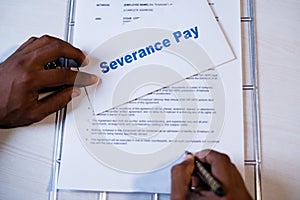 POV shot of employee checking severance pay notice and signing on termination agreement or contract - concept of job loss during