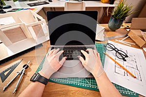 POV Shot Of Female Architect Working In Office On Plans For New Building Using Laptop