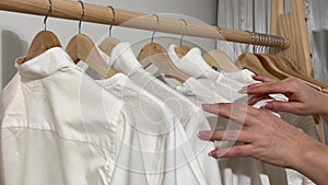 Pov shot of woman choosing outfit from large closet with stylish dresses. Close up of female hands looking through