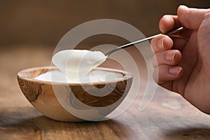 Pov shot of young female hand with full spoon of yogurt sitting at the table