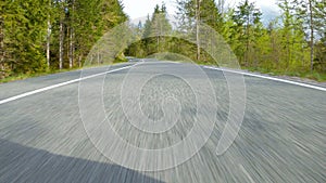 POV: Speeding down empty winding road running through forest in a fast supercar.