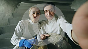 POV of Two young fencers man and woman have online video call with trainer using smartphone camera after fencing