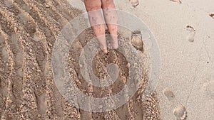 POV view walking on a sandy beach in circles trampling down mysterious spiral pattern. Following an elderly lady drawing
