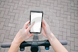 POV of woman hands using smartphone while standing with an electric scooter.