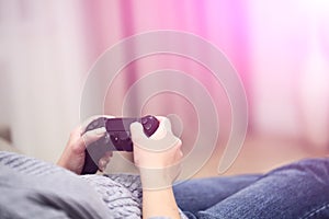 POV Woman lying on the coach in front of TV and holding in hands wireless game controller. Game addiction concept.