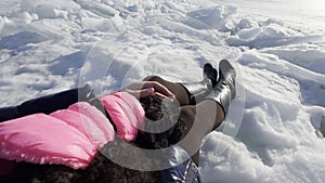 POV woman sitting on ice drifts at frozen sea with cute toy poodle dog on laps. Female person stroking puppy during