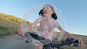 POV of a young girl enjoying a bicycle ride on the rural countryside