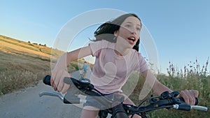 POV of a young girl enjoying a bicycle ride on the rural countryside