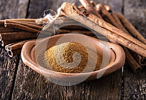 Powder of cinnamon in a pottery on wooden table