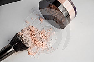 Powder hill, black makeup brush, a jar of powder lying on the edge