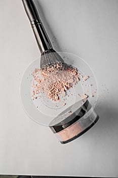 Powder hill, black makeup brush, a jar of powder lying on the edge