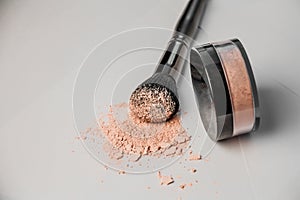 Powder hill, black makeup brush, a jar of powder lying on the edge