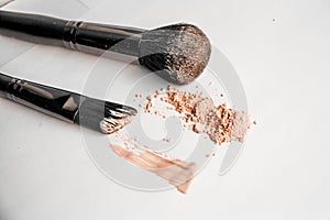 Powder slide, a touch of foundation and two black makeup brushes