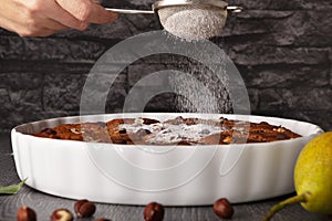 Powder sugar falls on chocolate hazelnuts cake