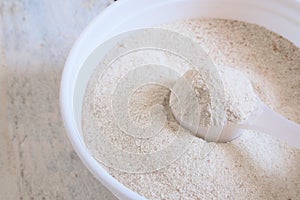 Powdered infant formula in a spoon while preparing child food mash next to a baby bottle.