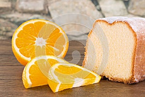 Powdered lemon cake with fresh sliced orange fruits on a wooden