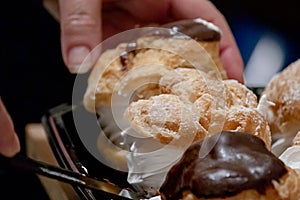 Powdered sugar and chocolate glased cream puffs filled with a swirl of white whipped cream