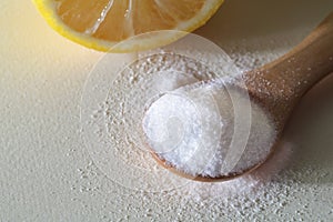 Powdered Vitamin C on wooden spoon with cut lemon on white background