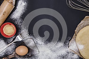 Powdering by flour rolled out dough for bakary stics with wooden rolling pin over black basground.