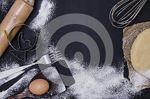 Powdering by flour rolled out dough for bakary stics with wooden rolling pin over black basground.