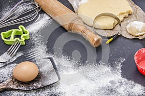 Powdering by flour rolled out dough for bakary stics with wooden rolling pin over black basground.