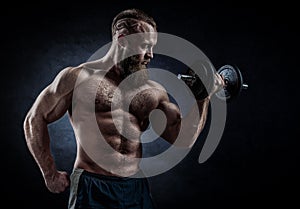 Power athletic bearded man in training pumping up muscles with d