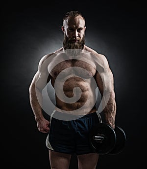 Power athletic bearded man in training pumping up muscles with d