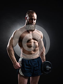 Power athletic bearded man in training pumping up muscles with d