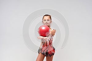 The power of balance. Flexible cute little girl child gymnast exercising using red ball isolated on a white background