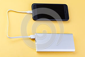 Power bank charges your smartphone  on yellow background. Universal external battery for gadgets. Power bank for charging mobile