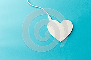 The power bank is connected to the heart on blue background. The concept of a healthy lifestyle. Modern technologies