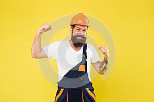 Power building. Strong construction man flex arms yellow background. Bearded man wear hard hat and work uniform